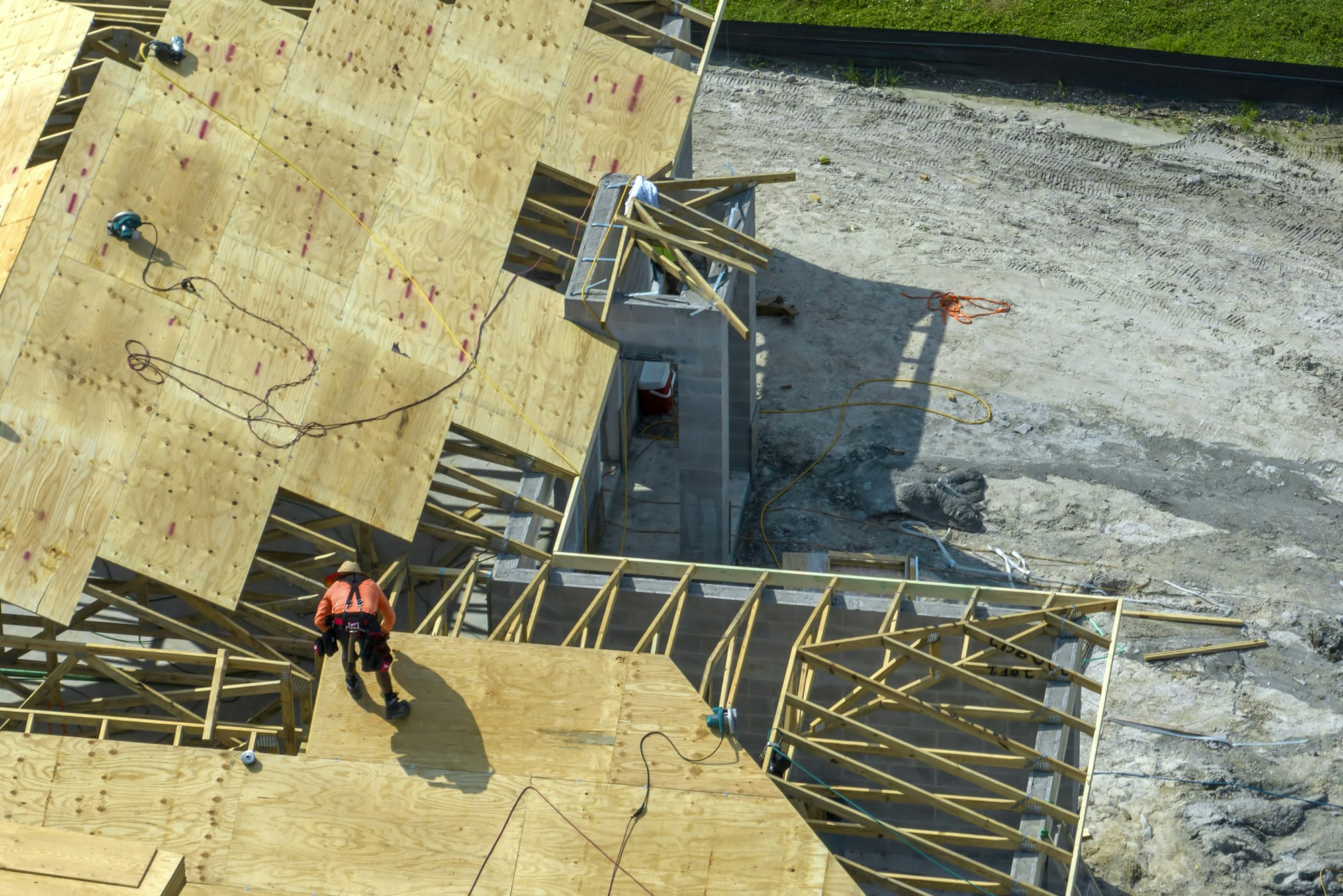 Professional builders working on roof construction of unfinished suburban home